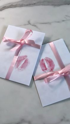 two folded greeting cards with pink ribbon tied around the edges and lips painted on them