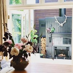 a vase with flowers sitting on a table in front of a fire place and window