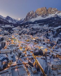 an aerial view of a town with mountains in the background and snow on the ground