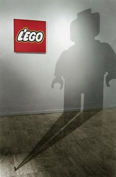 the shadow of a man holding an umbrella in front of a lego sign