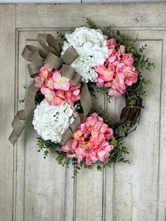 a wreath with pink and white flowers is hanging on the front door to decorate it