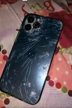 an iphone that has been broken and is laying on a bed with the screen cracked off