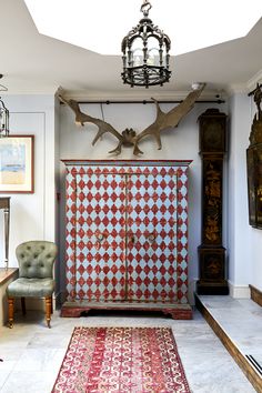 a red and white cabinet with antlers on it in the corner of a room