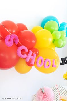 balloons and streamers are hanging from the wall in front of a birthday party backdrop