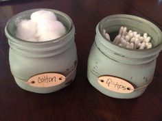 two jars filled with cotton sitting on top of a wooden table