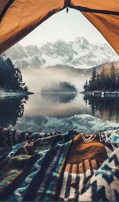 the inside of a tent with a lake and mountains in the background