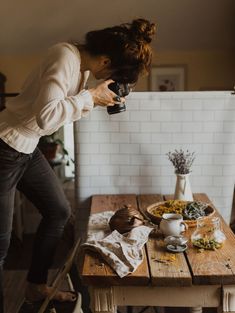 a woman is taking a photo with her camera on the table in front of some flowers