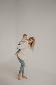 a woman holding a baby in her arms and posing for the camera with white background