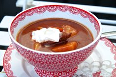 a red and white bowl filled with soup on top of a plate