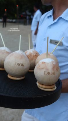 a man holding a tray with four wooden pops