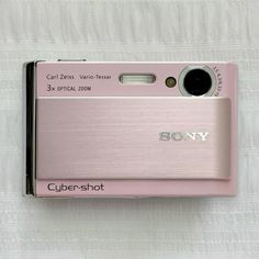 a pink camera sitting on top of a white sheet