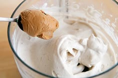 a spoon with some food in it on top of a glass bowl filled with ice cream