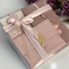 a box that has some jewelry inside of it and flowers in the background on a table