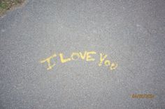 i love you written in yellow chalk on asphalt