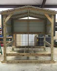 a wooden structure with wire in the middle and wood framing around it, sitting on top of concrete flooring