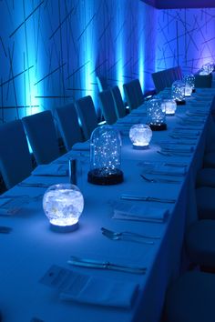 a long table with snow globes sitting on it's sides and place settings