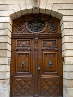 an old wooden door with intricate carvings on the front and side panels, in a stone building