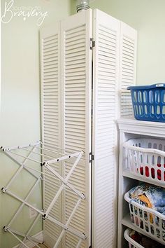 a closet with white shutters and baskets in it