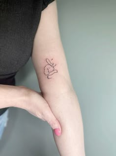 a woman's arm with a small tattoo of a rabbit on the left side