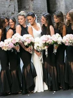 a group of women standing next to each other holding bouquets in their hands and wearing black dresses