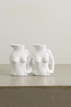 two white vases sitting on top of a table