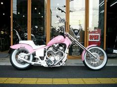 a pink motorcycle parked in front of a store