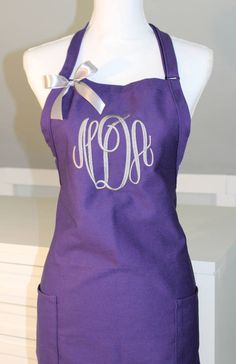 a purple apron with the letter monogram on it and a bow at the front