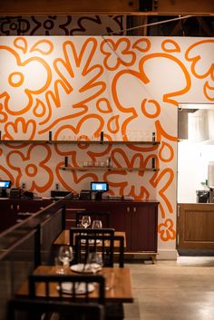 the interior of a restaurant with an orange and white mural on the wall behind it