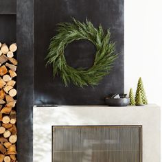 a fireplace with logs and a wreath on the mantle