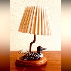 a lamp that is sitting on top of a wooden table next to a bird figurine