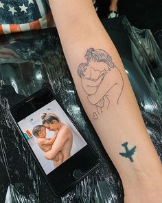 a woman's arm with a tattoo on it and an image of a man hugging her