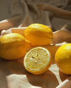 three lemons and one orange on a cloth