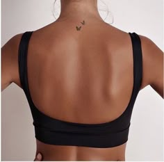 the back of a woman's neck with a butterfly tattoo on her left side