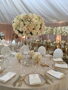 the table is set with white flowers and silverware for an elegant wedding reception at the four corners of the room