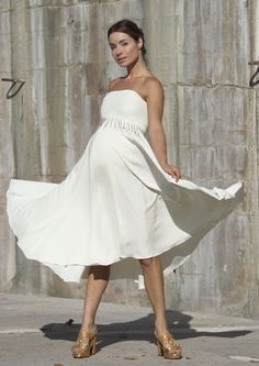 a woman in a white dress is walking down the street