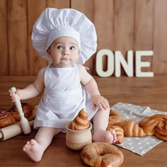 a baby sitting on the floor next to some croissants and doughnuts