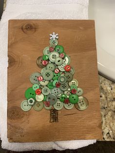 a christmas tree made out of buttons on a wooden board