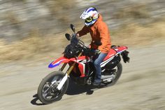 a man riding on the back of a red motorcycle