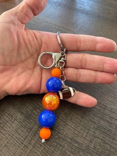 a person's hand holding a multicolored beaded keychain