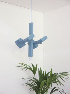 a potted plant sitting in front of a white wall with a blue light fixture hanging from it's side