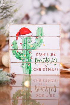 a wooden sign that says don't be prickly it's christmas with a santa hat on top