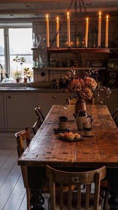 a wooden table sitting in the middle of a kitchen with candles on top of it