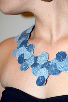 a close up of a woman wearing a necklace made out of blue denims and leaves