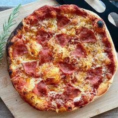 a pizza sitting on top of a wooden cutting board next to a knife and fork