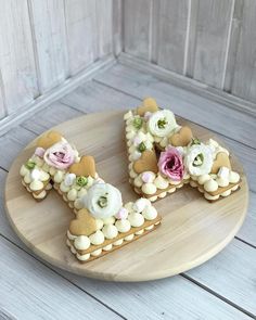 two cookies decorated with flowers are on a wooden platter, ready to be eaten