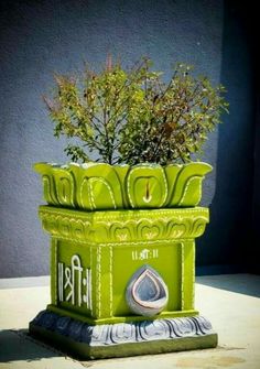 a green planter sitting on top of a cement slab next to a building wall