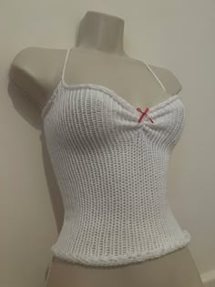 a woman's white tank top on a mannequin headdress with red pins