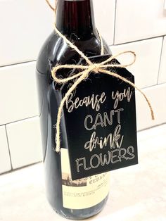 a wine bottle wrapped in twine with a sign that says, because you can't drink flowers