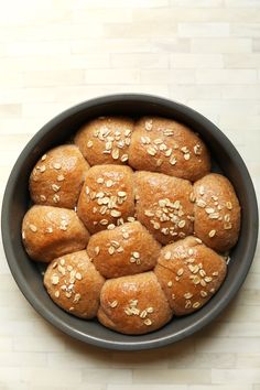 a bowl filled with buns covered in sesame seeds on top of a wooden table