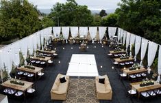 an outdoor seating area with couches, tables and lights on the side of it